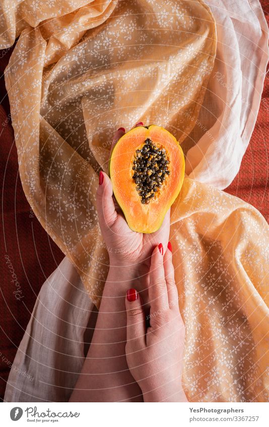 Papaya half hold in woman hands on tablecloths. Fruit Dessert Breakfast Organic produce Vegetarian diet Diet Exotic Healthy Eating Sweet Orange above view