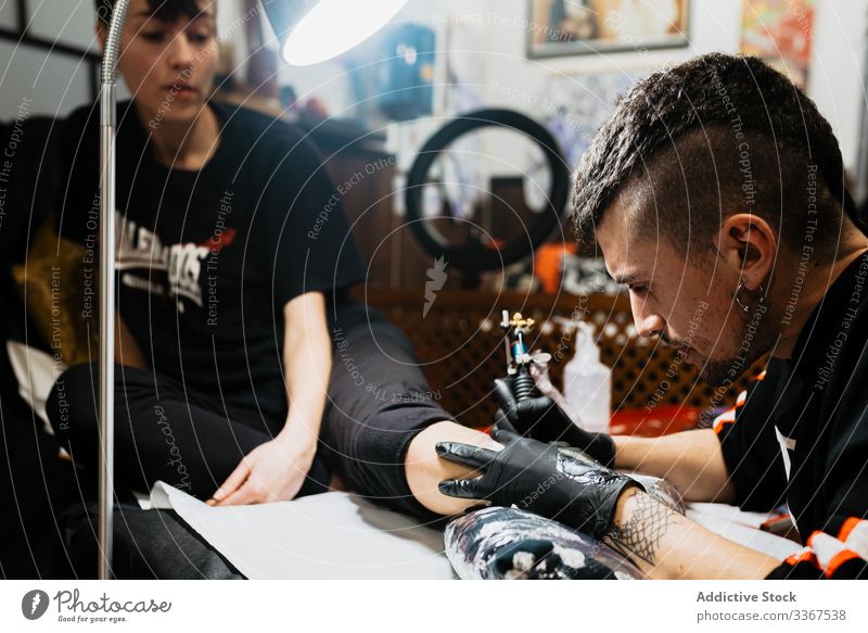 Tattooist working with client in salon tattooist man tool stylish subculture artist master creative fashion professional tattooer modern contemporary customer