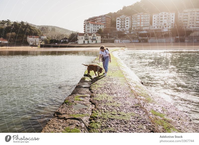 Woman with dog walking on stone pier woman building water sea together pet coast animal lifestyle female young casual friendship spain lekeitio basque country