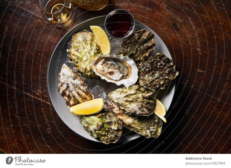 Fresh oysters with lemons in restaurant seafood clam shellfish sauce colorful platter dish delicacy gourmet epicure dinner fresh delicious healthy raw industry