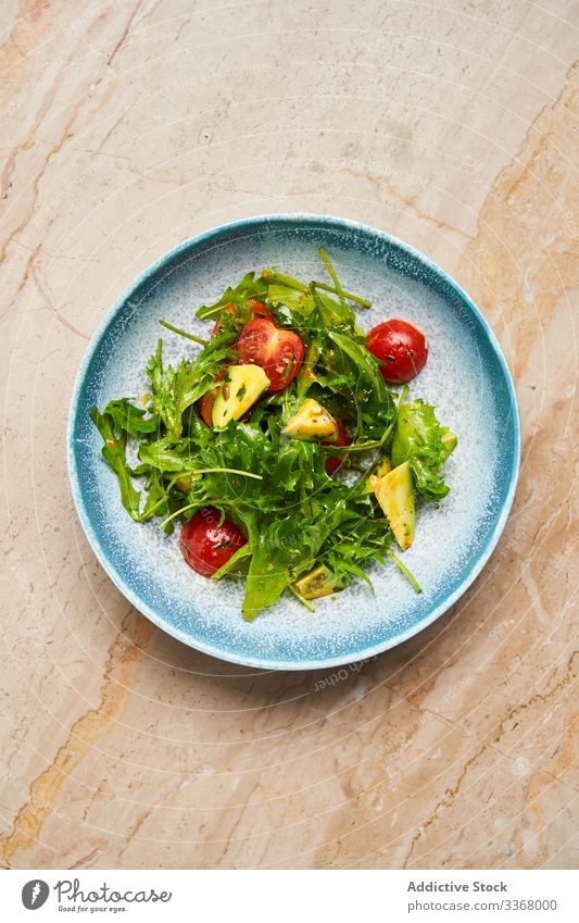 Fresh vitamin salad with rocket and tomatoes avocado arugula olive oil bowl plate dish restaurant vegetable slice herb sauce stylish elegant haute cuisine
