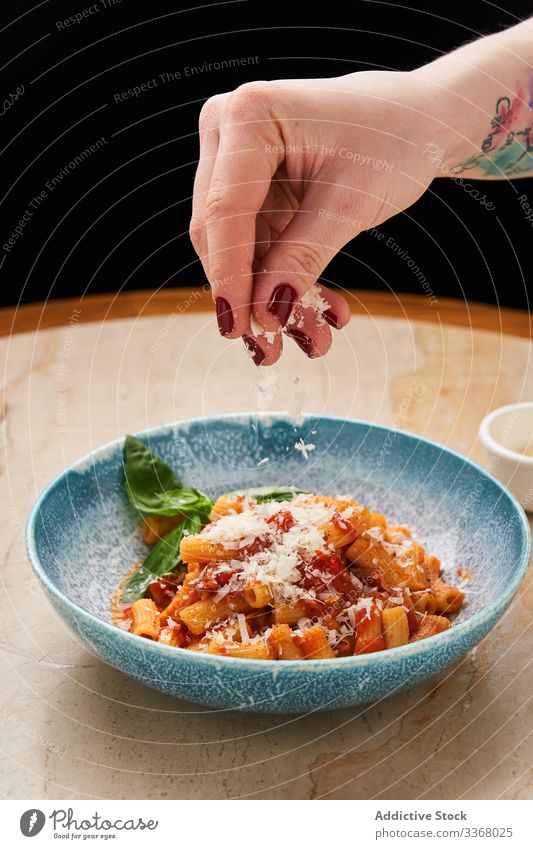Anonymous chef serving pasta in bowl cooking noodles sparkling cheese grated tomato sauce plate setting preparing italian food traditional restaurant dish herb