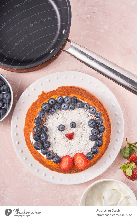 Cake with berries on plate cake baked dessert cooking decorating blueberry strawberry sour cream female chef homemade household penguin dish bowl coconut hand