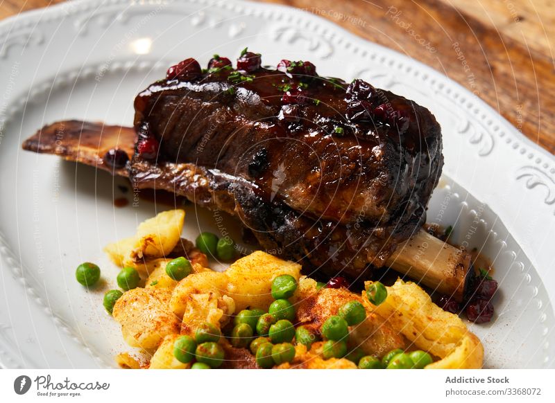 Delicious meat with berry sauce and potatoes steak restaurant roasted dish baked bbq peas garnish bone plate service meal food haute cuisine luxury rich