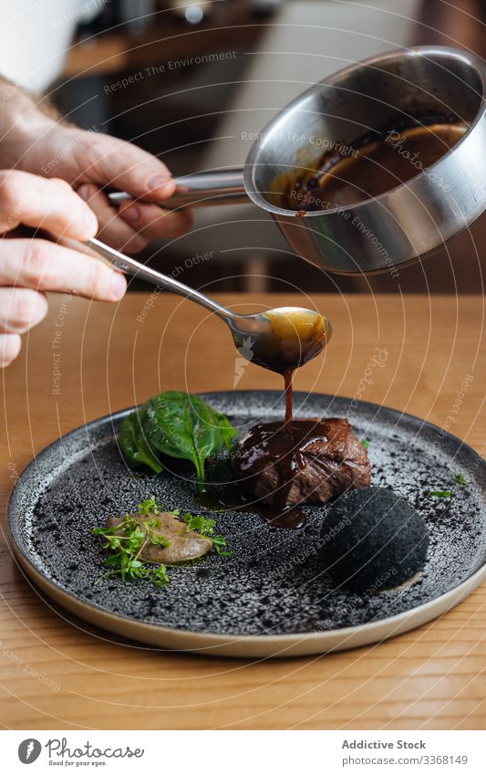 Person preparing meat steak with sauce and herbs gourmet dish delicacy high cuisine restaurant food delicious meal plate roast basil leaf tasty delicatessen