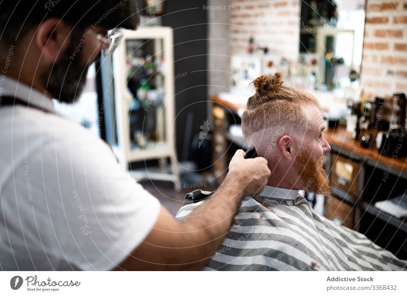Hairdresser cutting a redhead man hair client trendy hairdresser barbershop bearded masculinity customer care salon hipster hairstylist handsome stylish