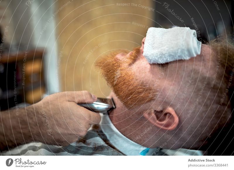 Barber trimming redhead man beard men client trendy hairdresser barbershop masculinity customer care salon hairstylist handsome stylish relaxing stress relief