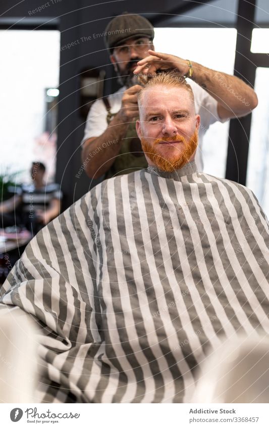 Hairdresser cutting a redhead man hair client trendy hairdresser barbershop bearded masculinity customer care salon hipster hairstylist handsome stylish