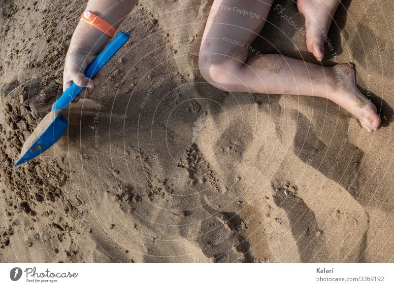 a child plays barefoot in the sand with a shovel Playing Child Shovel Sand family vacation Feet Summer leg Water fun Boy (child) Barefoot People human Nature