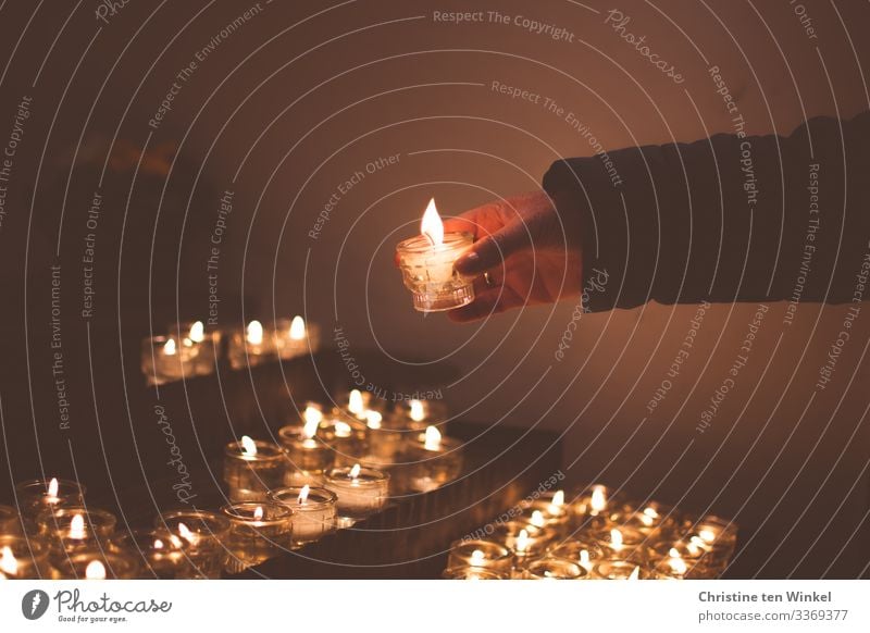 Woman lighting a candle on a candle altar Adults Hand 1 Human being 30 - 45 years 45 - 60 years Church Candlelight Candle flame Glass candle holder Candle altar