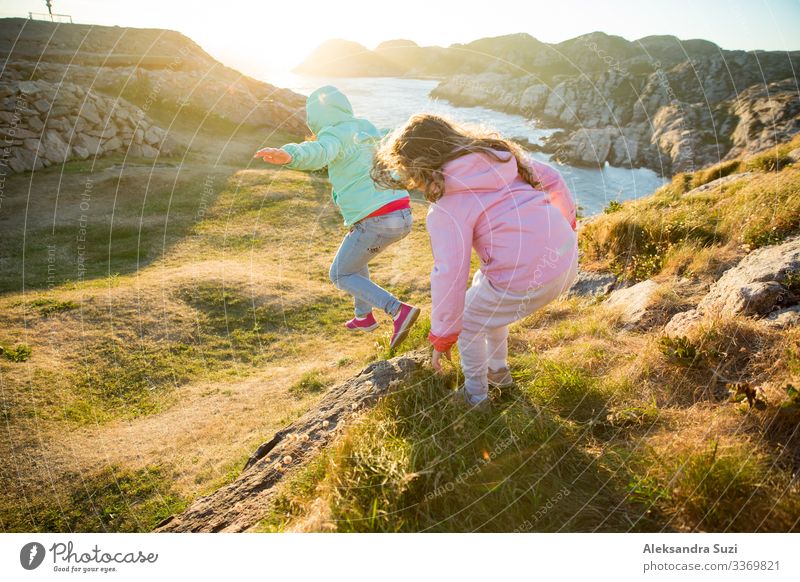 Two little girls play on rocky northern seashore. Run, laugh, jump, explore the coastal rocks and mountains. Travel and enjoy a great adventure in Norway.