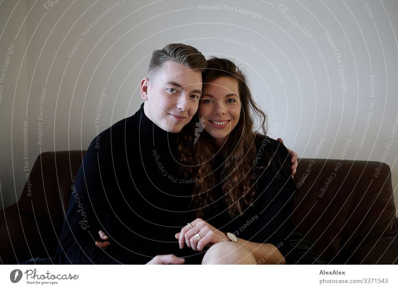 Young man and young woman sitting together on a brown leather couch and smiling Style Joy already Harmonious Flat (apartment) Sofa Young woman