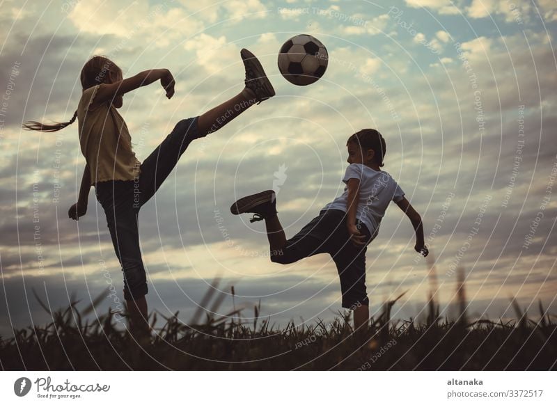 Happy young little boy and girl playing in the field with soccer ball. Kids having fun outdoors. Concept of sport. Lifestyle Joy Leisure and hobbies Playing