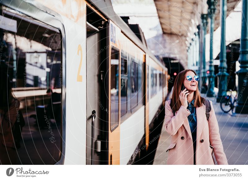 young woman at train station using mobile phone. Travel concept screen destination travel backpack caucasian europe railway waiting track wagon arrival long