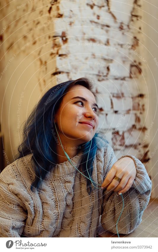 Young adult female with dyed blue hair listening music in a coffee shop during blue hour, shallow selective focus Adults Asians Blue Casual clothes Café Cozy