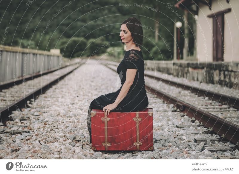 young woman sitting on a suitcase on railway station beautiful elegant elegance romantic fragility love femininity dress nostalgia freedom beauty outdoors