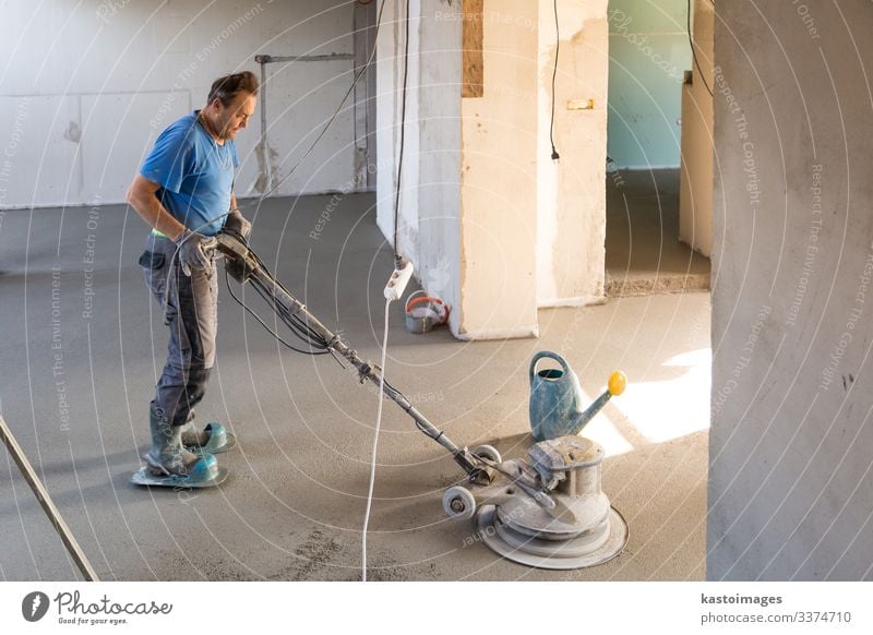 Laborer polishing sand and cement screed floor. Work and employment Craftsperson Human being Man Adults Sand Building Concrete Cement construction Story float
