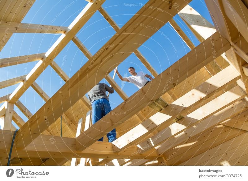 Builders at work with wooden roof construction. house frame home builder carpenter roofer worker lumber building development tool workman timber hardhat