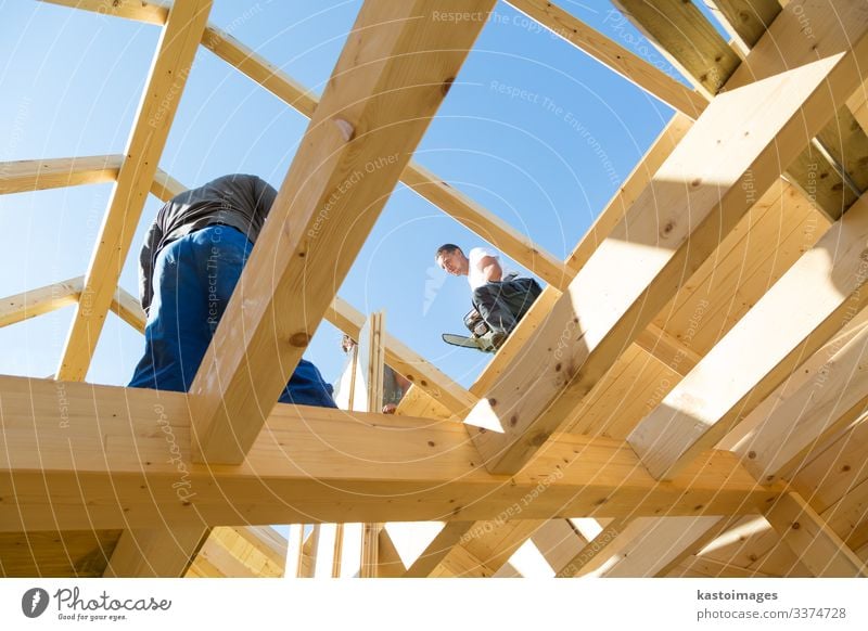 Builders at work with wooden roof construction. house frame home builder carpenter roofer worker lumber building development tool workman timber hardhat