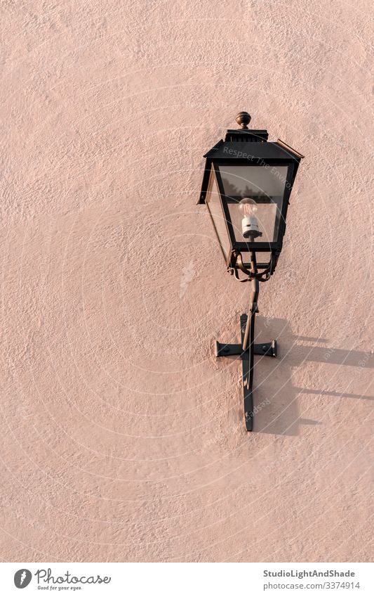 Streetlight on a textured pink wall streetlight streetlamp lantern electricity painted stone background surface dusty pink pastel metal old ancient concrete