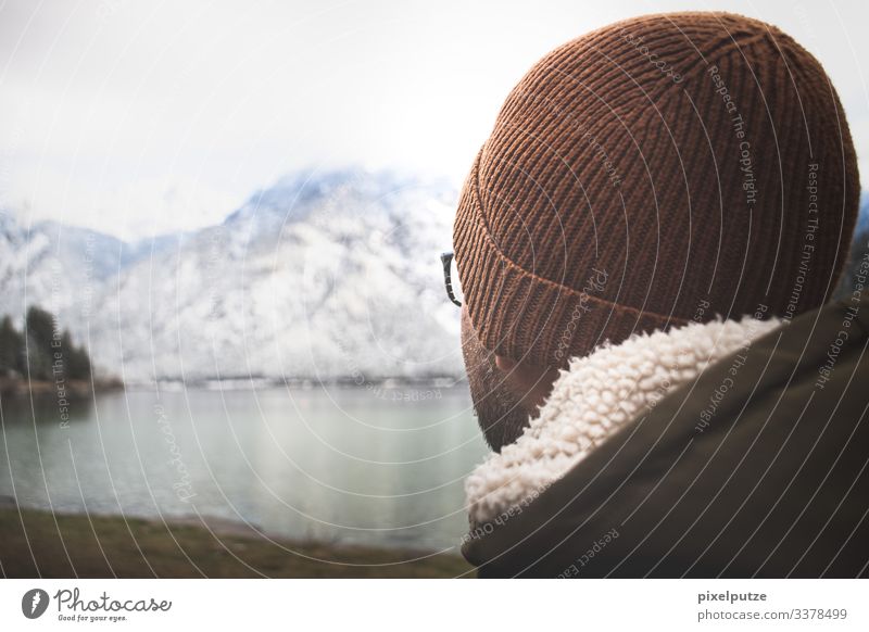 Man with cap looks at mountain lake Alps Bavaria mountains Eyeglasses Nature outdoor Lake wide Winter Hiking