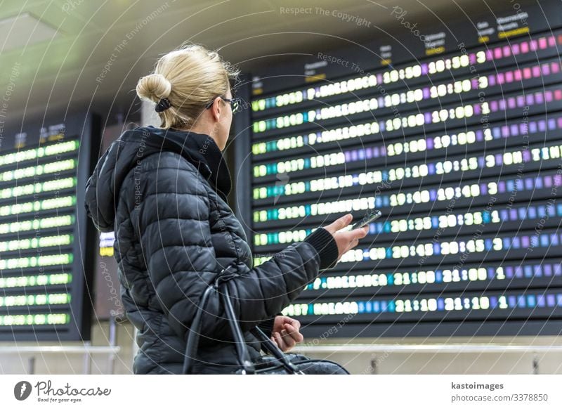 Woman at airport looking at the flight information board. Vacation & Travel Tourism Trip Winter Decoration Telephone PDA Aviation Human being Adults Airport