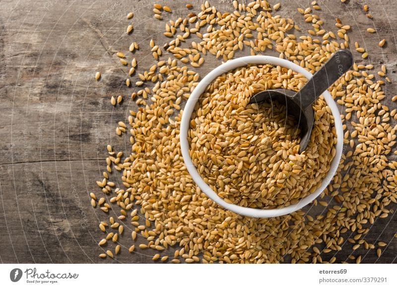 Golden flax seeds in bowl on wooden table. Top view. Copy space food cereal dry agriculture grain healthy organic brown raw barley buckwheat groats heap