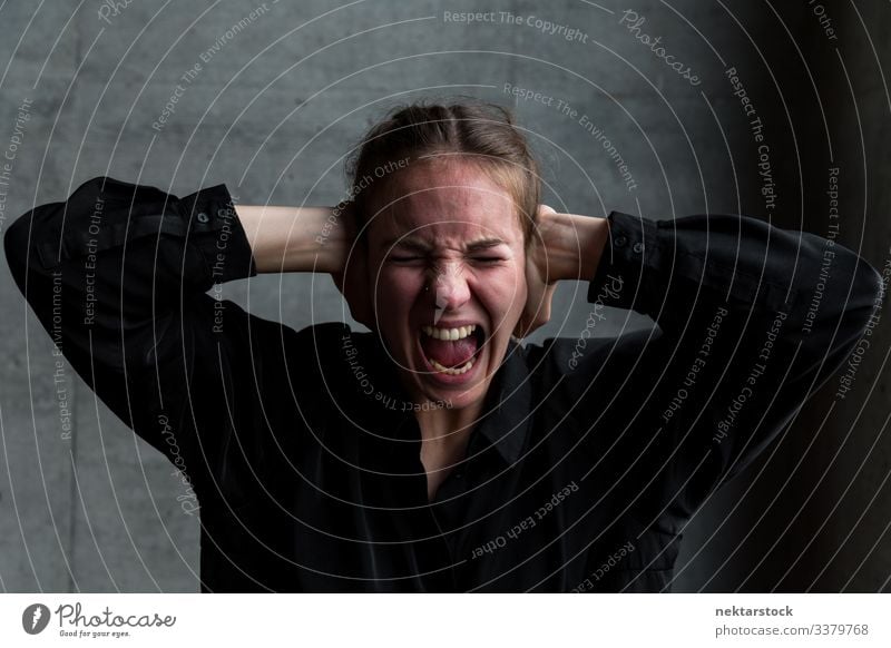 Young Woman Screaming in Agony with Hands Covering Ears hands on head scream female girl anguish woman young adult terror horror real life real person