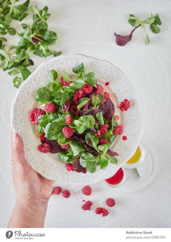 Person holding plate with raspberry and spinach salad cook fresh organic sweet delicious tasty natural green vegetarian healthy diet food leave dessert plant