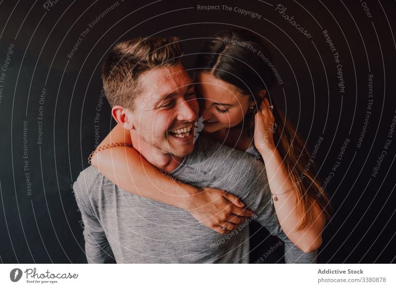 Cheerful couple having fun while relaxing together after training in dark modern fitness studio laugh cheerful piggyback enjoy flirt love hug athlete embrace