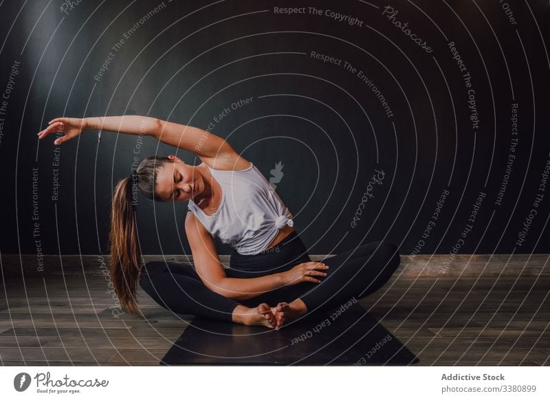 Slender barefooted woman stretching body in bound angle pose in contemporary studio yoga practice exercise training athletic workout position spirituality