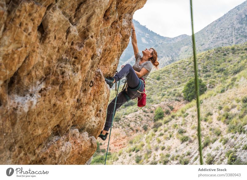 Active female climber ascending on cliff woman alpinist mountain practice climbing active mountaineering risk travel brave adventure courage altitude extreme