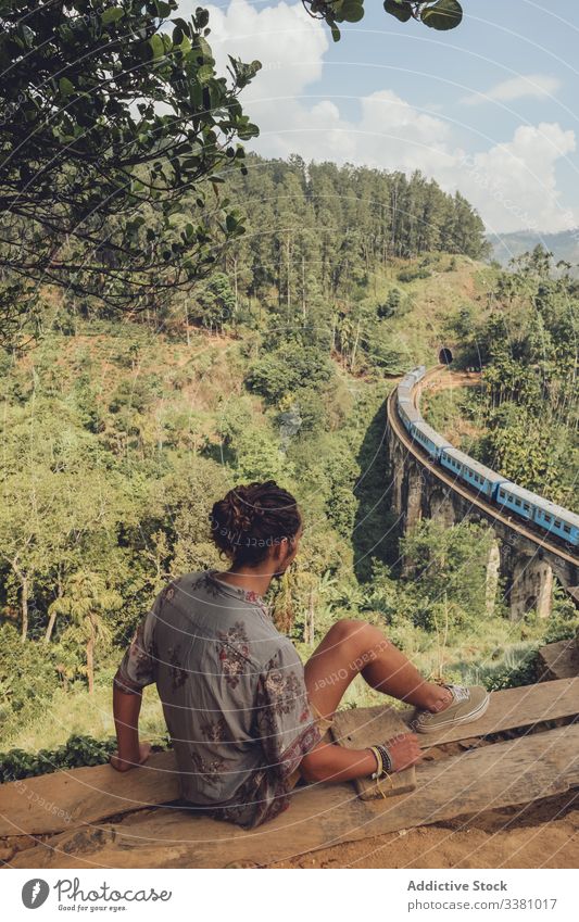 Anonymous man on vacation enjoying view from peak of hill viewpoint tourism bridge landscape tropical travel train railroad trip green tree plant nature journey