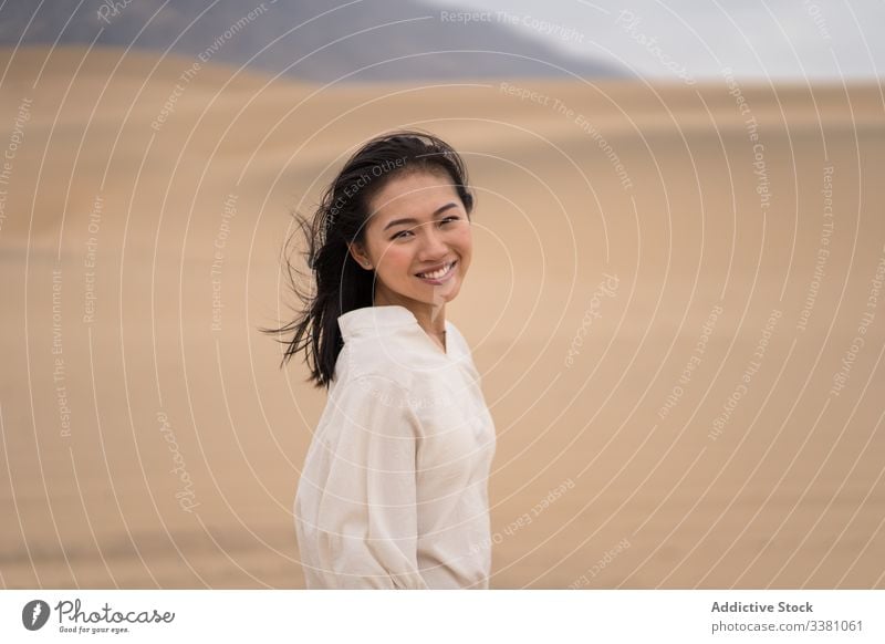 Cheerful young ethnic female tourist enjoying vacation in desert woman sandy explore tourism travel nature adventure dry traveler beauty freedom happy journey