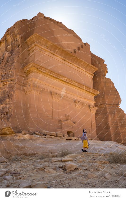 Excited female tourist enjoying sightseeing in desert woman tomb carved cliff traveler freedom vacation tourism culture grave religion architecture old location