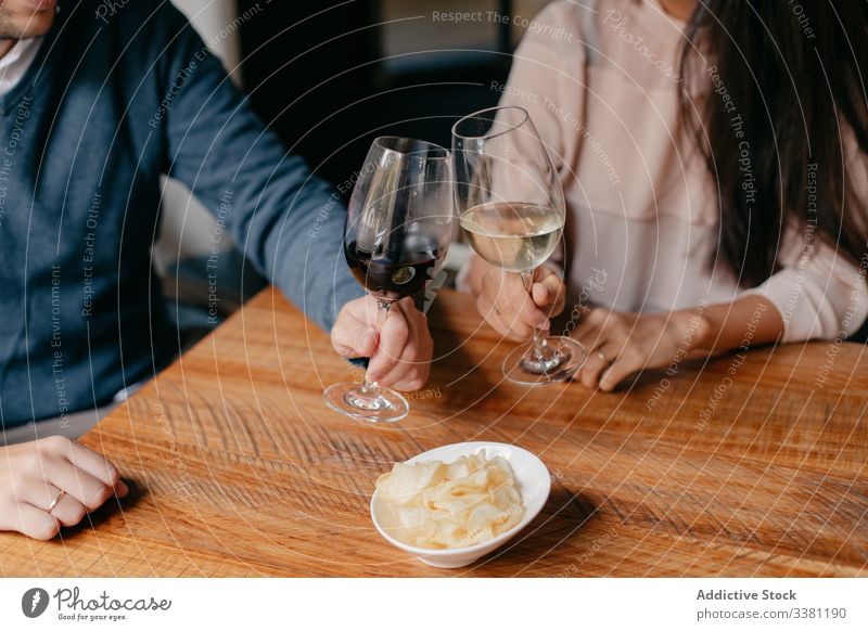Anonymous couple clinking with wine glasses in cafe toast happy romantic young together celebrate love relationship affection cheerful date drink alcohol