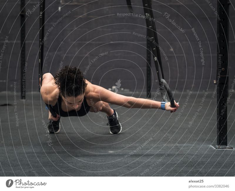 Female athlete hanging on gymnastic rings in gym stock photo