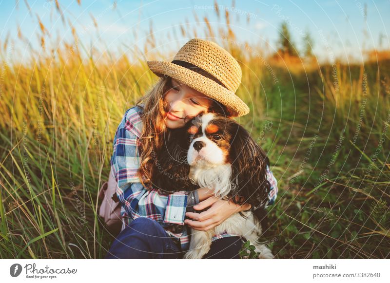 happy child girl enjoying summer vacations with her dog, walking and playing on sunny meadow. Traveling, exploring new places and rural living concept nature