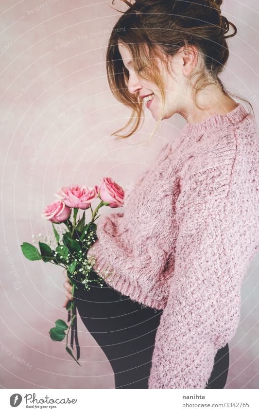 Young pregnant woman holding a bouquet of roses pregnancy mom waiting family love third trimester month weeks natural real candid real woman people flowers pink