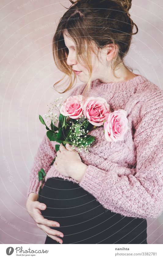 Young pregnant woman holding a bouquet of roses pregnancy mom waiting family love third trimester month weeks natural real candid real woman people flowers pink