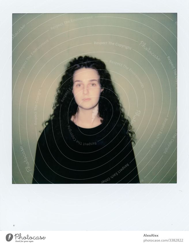 Analog Polaroid portrait of a young woman in front of a green wall Looking into the camera Portrait photograph Central perspective Shallow depth of field