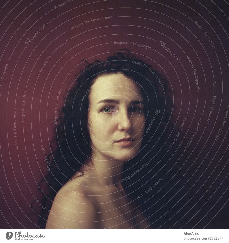 Analogue portrait of a young woman in front of a red wall Looking into the camera Portrait photograph Central perspective Shallow depth of field