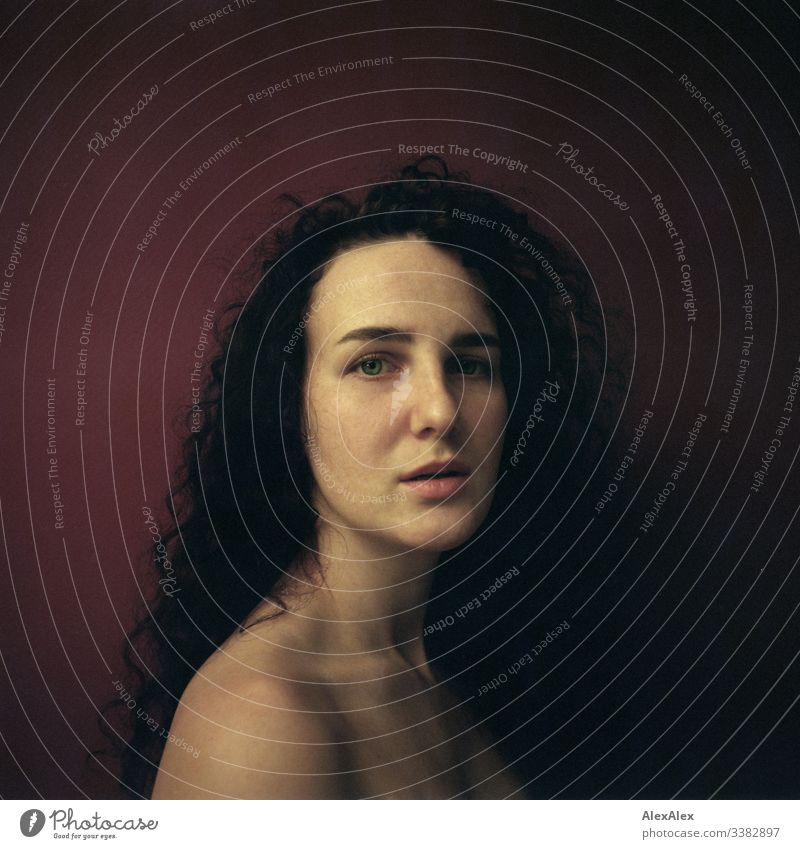 Analogue portrait of a young woman in front of a red wall Looking into the camera Portrait photograph Central perspective Shallow depth of field