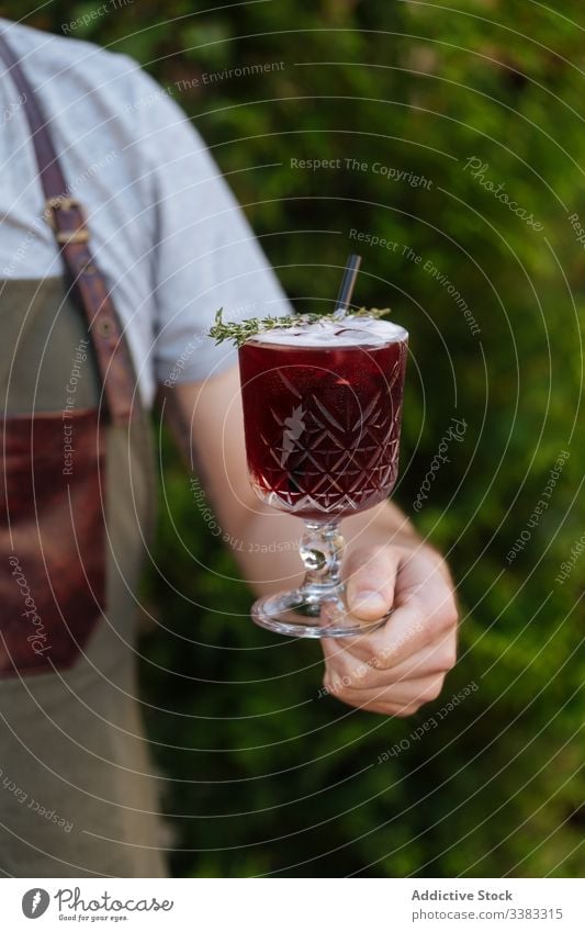 Anonymous waitress holding red appetizing drink in glass beverage fresh cocktail delicious tasty berry organic festive alcohol fruit juice natural party plant