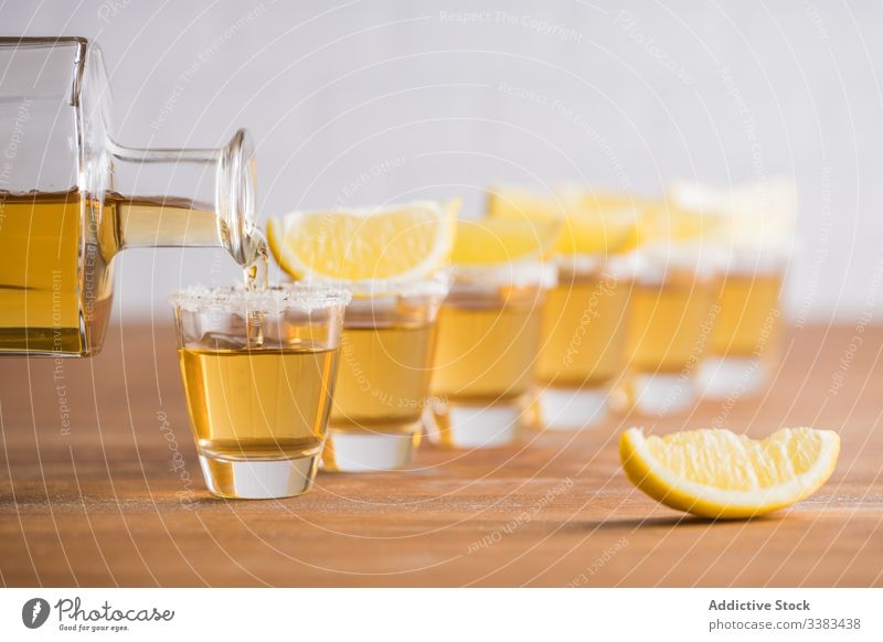 Shots of alcohol with slices of lemon on top shot tequila piece booze row glass table wooden wall drink beverage refreshment tasty cold orange citrus bar juice