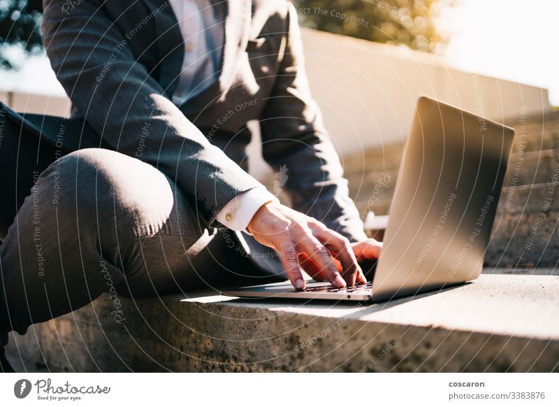 Smiling young business man sitting on steps with laptop and coffee. adult beard bearded businessman caucasian city computer concept connection employee