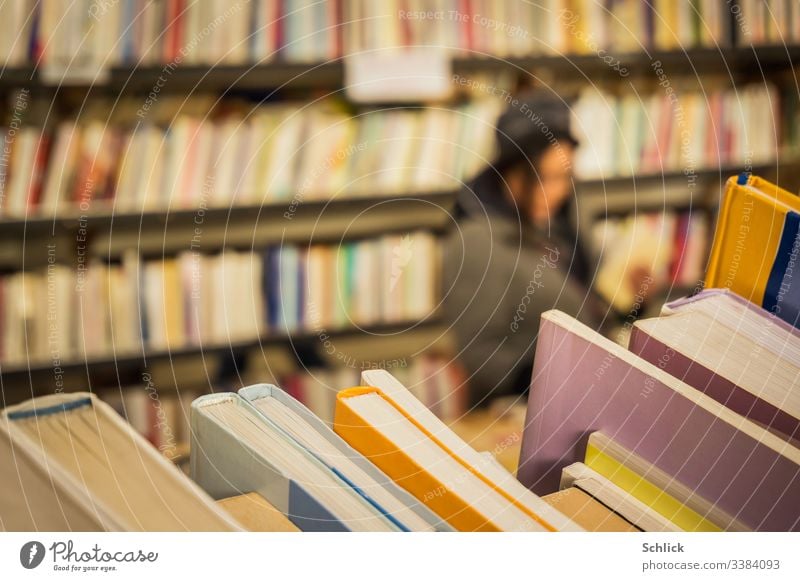 Close-up second hand books in a bookstore with a customer in blur Second-hand shop Woman selective focus bokeh Bookshelf Many Shallow depth of field Diagonal