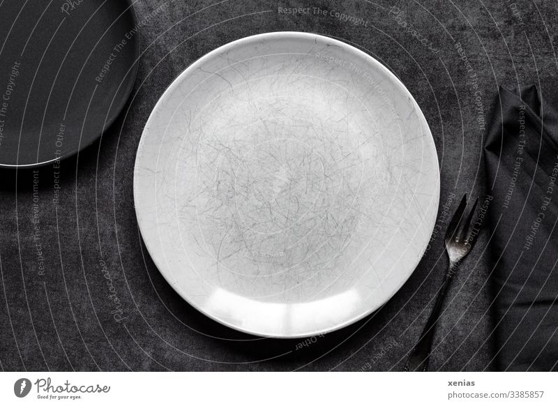 Light and dark round plate with fork on grey background Plate Empty Food photograph Round White Interior shot Nutrition Fork Napkin Table Black scratched Eating