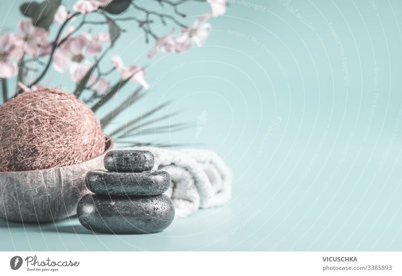 Zen stones with coco nut and towels at light blue background with flowers. Relaxing beauty day. Spa concept zen spa nobody relaxation closeup essentials