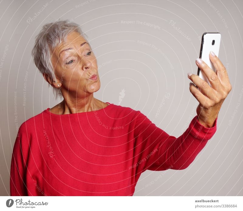 senior woman taking a smartphone selfie with duckface self portrait mature duck face pout mobile cell camera smart phone trend older lady adult photo photograph